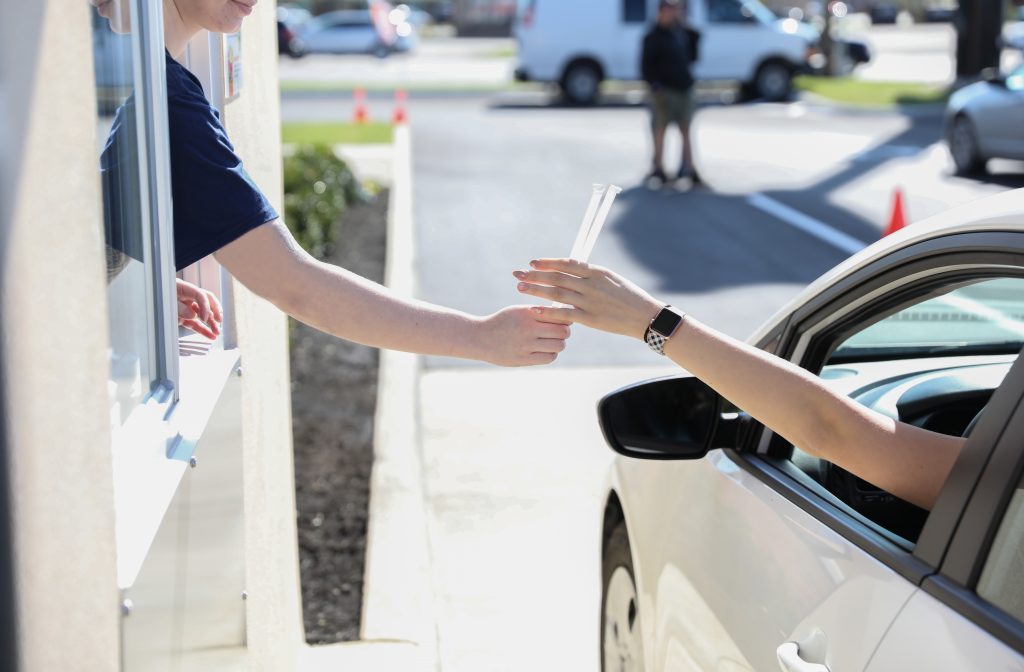 A drive-thru employee handing a driver their meal 