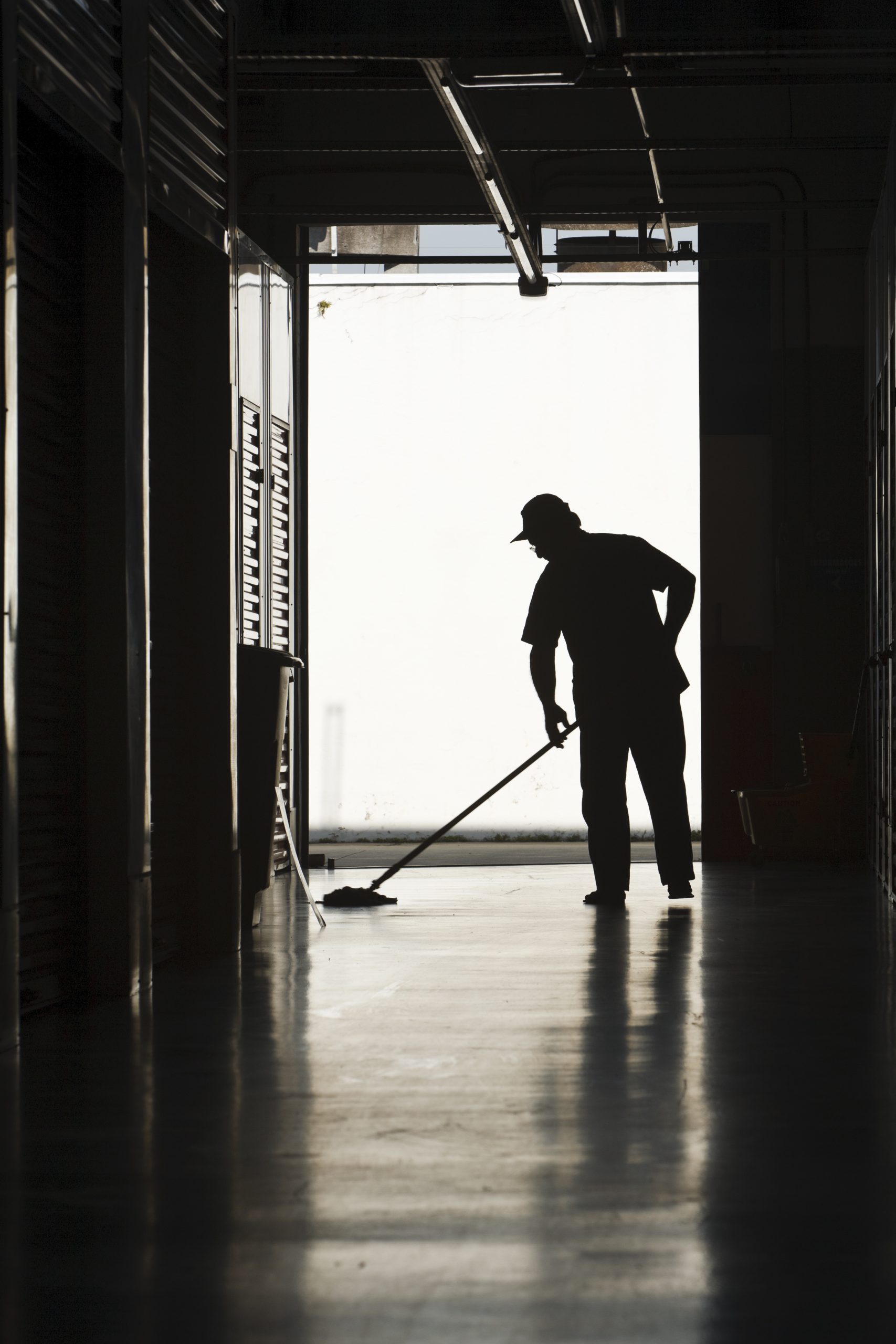 Silhouette of a man moping warehouse floor