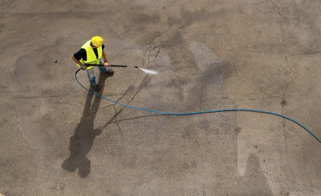 A man using power washing to clean an industrial floor