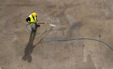 A man using power washing to clean an industrial floor