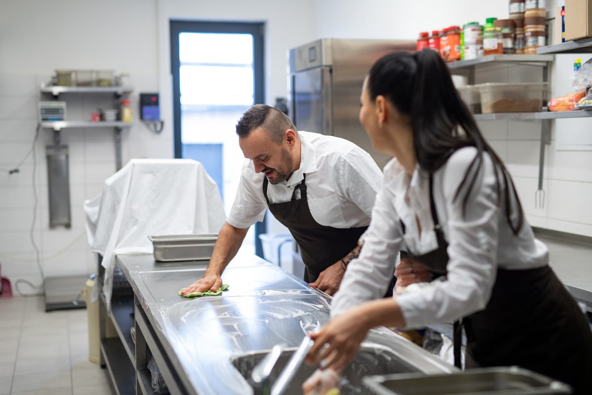 Two people in aprons cleaning the kitchen of a restaurant in El Paso.