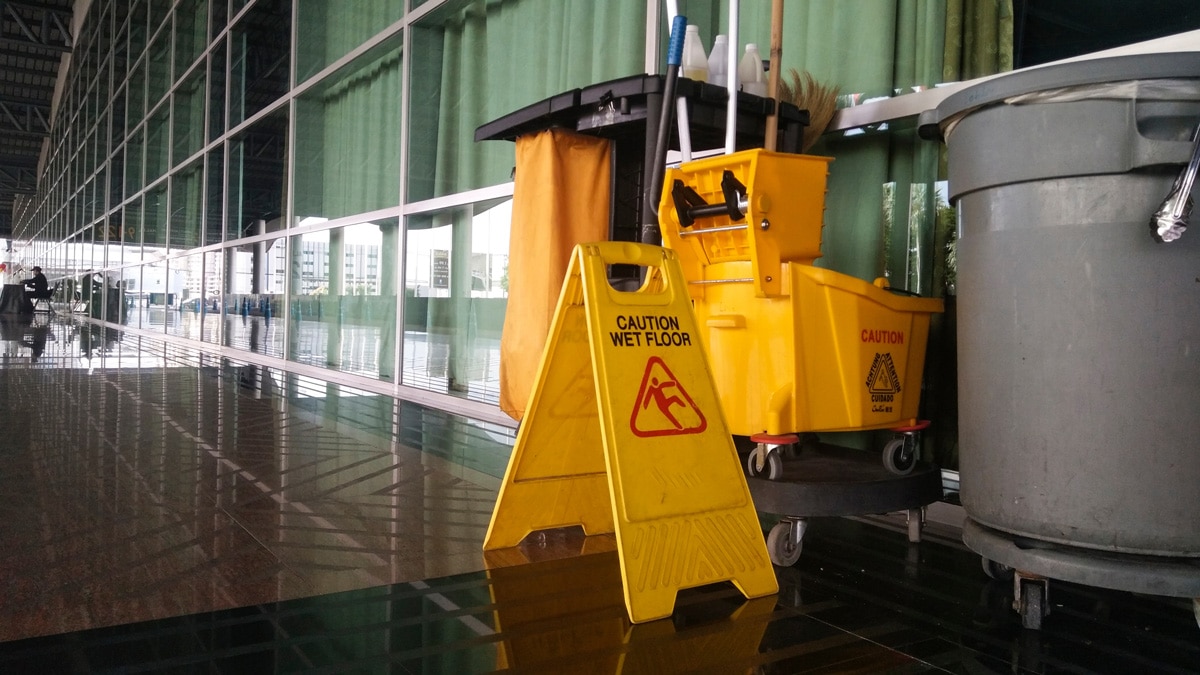 A cleaning cart and yellow “caution” sign in a commercial building in El Paso.